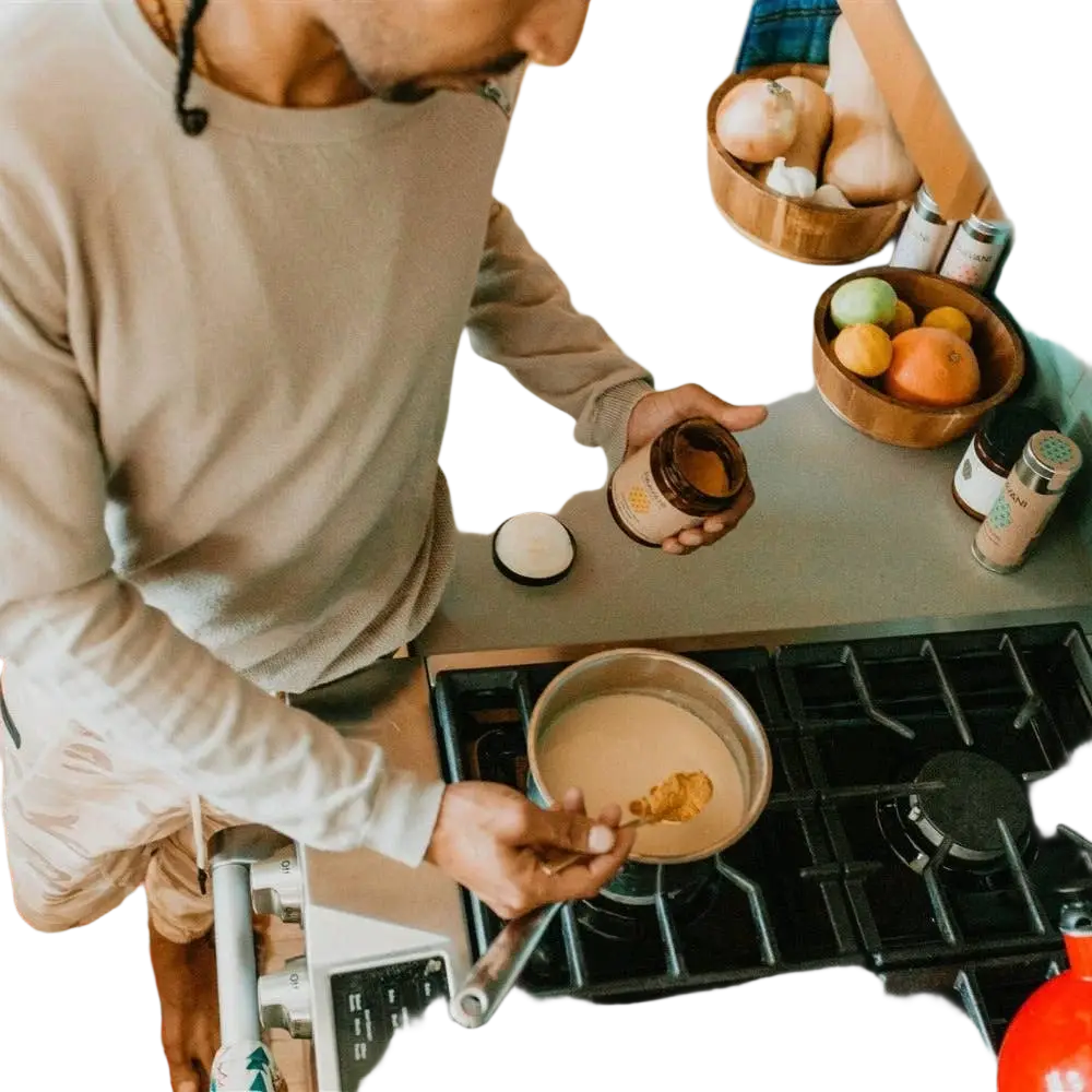Goldene Milch Gewürze von PAAVANI Ayurveda mit Kurkuma, Ingwer und Zimt für Gesundheit und Wohlbefinden, in einem Glas.