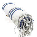 Ein aufgerolltes hamam spa handtuch aus Baumwolle mit weißen und ozeanblauen streifen und fransen bei mana shop