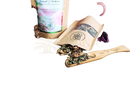 Ein hölzerner löffel mit gravierten blumenmotiven hält eine mischung aus getrockneten kräutern für chakra anahata grüntee
