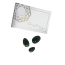Weiße rechteckige box mit goldgeprägtem mandala und text taking care of you neben drei glatten dunkelgrünen natural jade yoni eier pack steinen auf silbernem satin