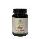 Dunkelbernsteine glasflasche mit schwarzem verschluss und ayurveda specialist etikett mit pinker blume enthält 60 vegacaps kanchanar zur unterstützung von hautgesundheit und hormonbalance