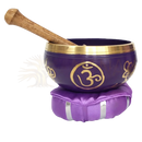 Lila klangschale kronenchakra mit goldenem om-symbol und spirituelle öffnung auf passendem kissen