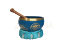 Blaue tibetische klangschale mit goldrand und halschakra symbol auf tuffgünner sitzunterlage für innere stimme mana shop