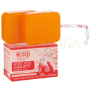 Zwei orangefarbene bars von koji white kojic acid dunkle-flecken-korrektur seife in rot-weiß verpackung mit frau in traditioneller kleidung