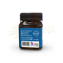 Dunkelbraunes glasgefäß mit schwarzem deckel und blauem etikett der rückseite von mad honey nepal himalayan cliff honey 250 g