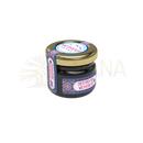 Ein kleiner dunkelglasbehälter mit goldenem deckel und blauen rosa weißen etiketten mad shilajit nepal