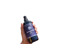 Dunkelblaue glasflasche magnesiumöl spray mit sprayzerstäuber und weißem etikett ancient purity volle absorption vor rosa rosen