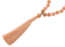 Peachfarbene quaste an orangefarbenen sonnensteinperlen und einem strukturierten holzperlen mala sonnenstein aus dem mana shop