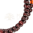 A string of polished dark red wooden beads with a single orange accent bead in mallah meditations-perle mala gebetskette