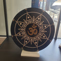Eine schwarze Vinyl-Schallplatte, verziert mit einem gold-weißen Punktmalerei-Mandala und einem zentralen Om-Symbol, präsentiert auf einem weißen Ständer.