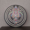 Eine Vinyl-Schallplatte, verziert mit einem farbenfrohen Punktmalerei-Mandala eines Elefantenkopfes und einer Lotusblüte, angelehnt an eine graue Strukturwand.