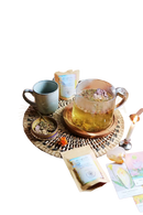 Ein klarer glaskrug mit goldenem naturals manifest tee und getrockneten lila blumen ideal für meditation