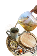 Klarer glas-teekessel mit henkel gefüllt mit goldenem naturals manifest tee ideal für meditation mit getrockneten blumen