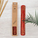 Roter Räucherstäbchenhalter „Elm“ aus Holz mit goldener Blumenverzierung neben der Verpackung und Räucherstäbchen.