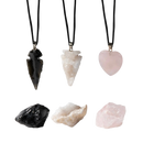 Drei myga eco geode-anhänger aus schwarzem obsidian rohstein mit rosa und weißem kristall an schwarzen kordeln