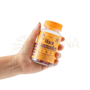 Eine hand hält eine transparente flasche mit oranger verschluss und hochwertige maca-extrakt maca gummies ideal für menschen