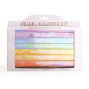 Eine weiße Verpackung für ein Chakra Balancing Kit mit sieben farbigen, gestapelten Päckchen mit Räucherstäbchen, die jeweils einem anderen Chakra zugeordnet sind.