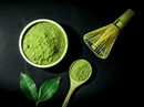 Matcha-Pulver, ein Bambusbesen und Blätter in diesem Bild.