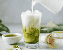 Milch wird in diesem Bild in einen Matcha-Latte gegossen.