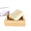 Eine blassgelbe, gesprenkelte bio-patchouli-seife von mademoiselle agathe in einem holzseifenhalter für empfindliche haut