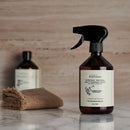 Dunkel bernsteinfarbene glas-sprühflasche mit schwarzer düse und weißem etikett eucalyptus dives geranium multi-surface cleaner