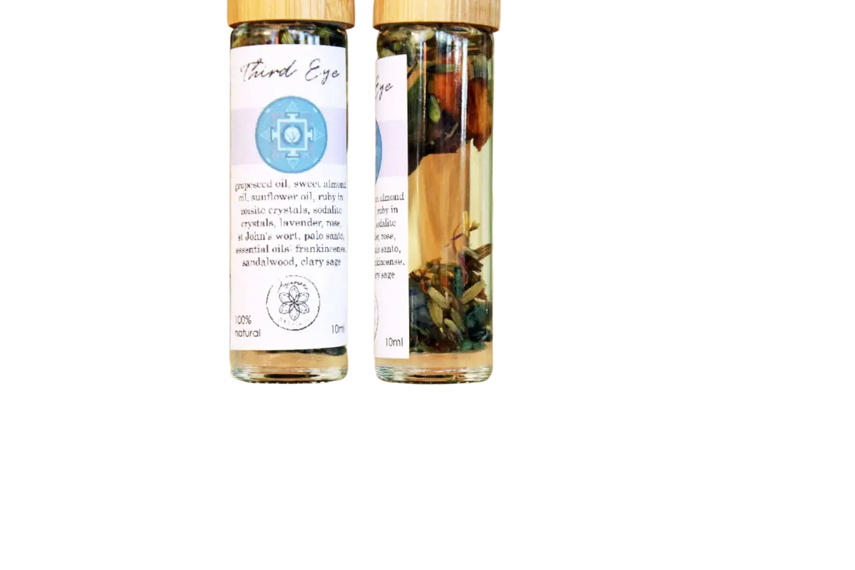 Ätherisches Öl für das dritte Auge mit Ajna Chakra, Kristallen und Kräutern von Ayamani Naturals, in einer dunklen Flasche.
