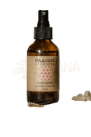 Ein bernsteinfarbenes glas-sprühflasche mit schwarzer düse und paavani ayurveda bulgarischem rosenwasser als beruhigender aromatherapie-nebel