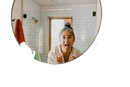 Runde, gerahmte badezimmerspiegel vor weißer fliesenwand mit paavani ayurveda kupfer zungenreiniger sichtbar