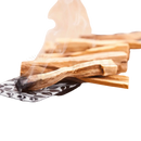 Ein smoldernder palo santo räucherholzstab auf schwarz-weiß gemustertem keramiktablett mit unbenutzten holzstäbchen von mana shop