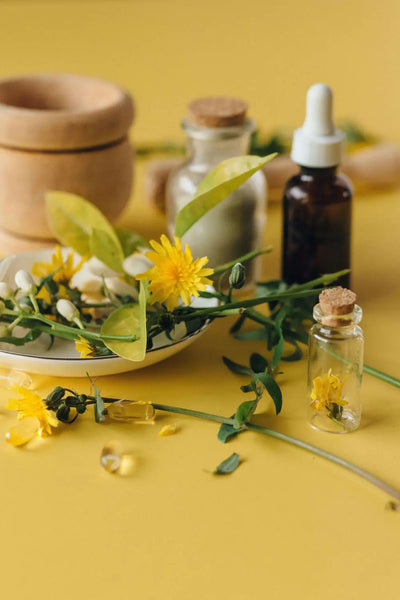 Gelbe Blumen, kleine Flaschen und Kräuter auf gelbem Hintergrund.