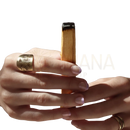 Eine hand hält ein premium palo santo bundle 80 g mit einem goldenen ring im sunburst-design von mana shop
