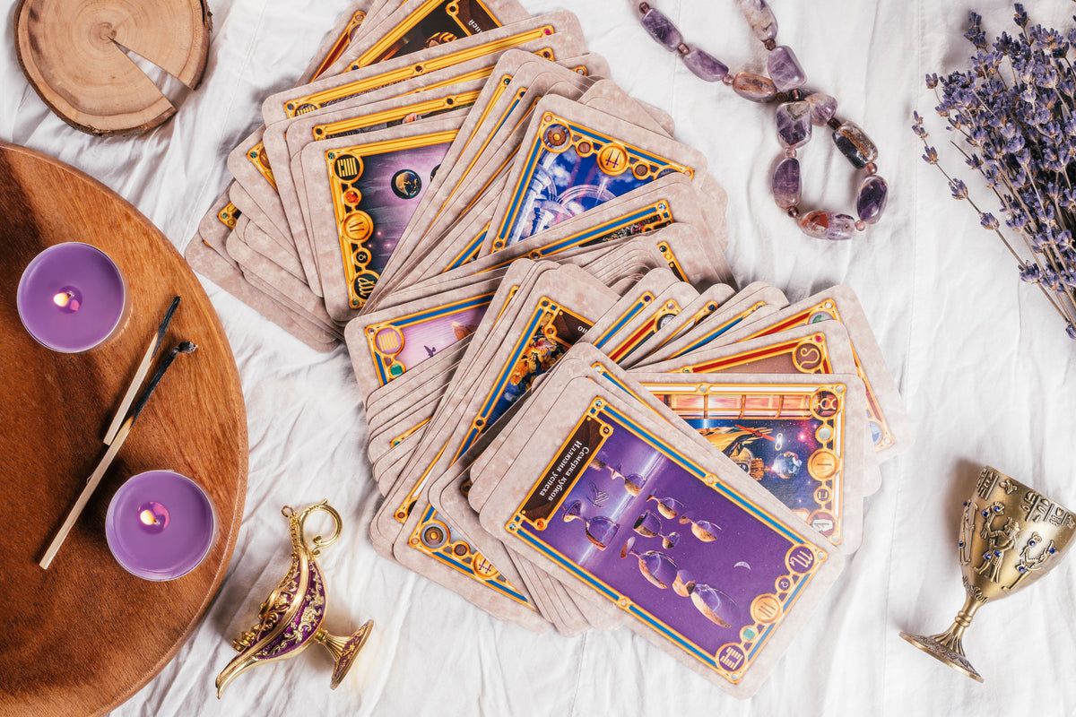 Orakelkarten, Lavendel, Amethyst-Kristalle und lila Kerzen auf weißem Tuch.