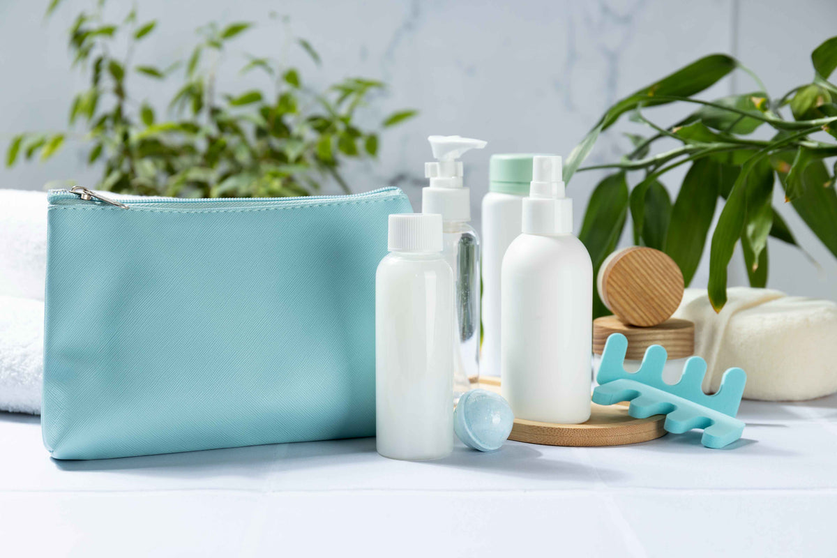 Hellblaues Kosmetiktäschchen mit Bio-Pflegeprodukten und Accessoires auf weißem Untergrund.