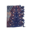 Ein gefalteter blauer Sarong mit rot-weißen Pfauenmustern und Fransenrand.