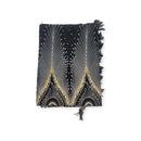 Ein gefalteter schwarzer Sarong mit weißen Pfauenfedermustern und goldenen Akzenten.