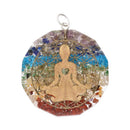 Ein kreisförmiger Orgon-Anhänger mit einer goldenen meditierenden Figur über geschichteten Steinen in Chakra-Farben.