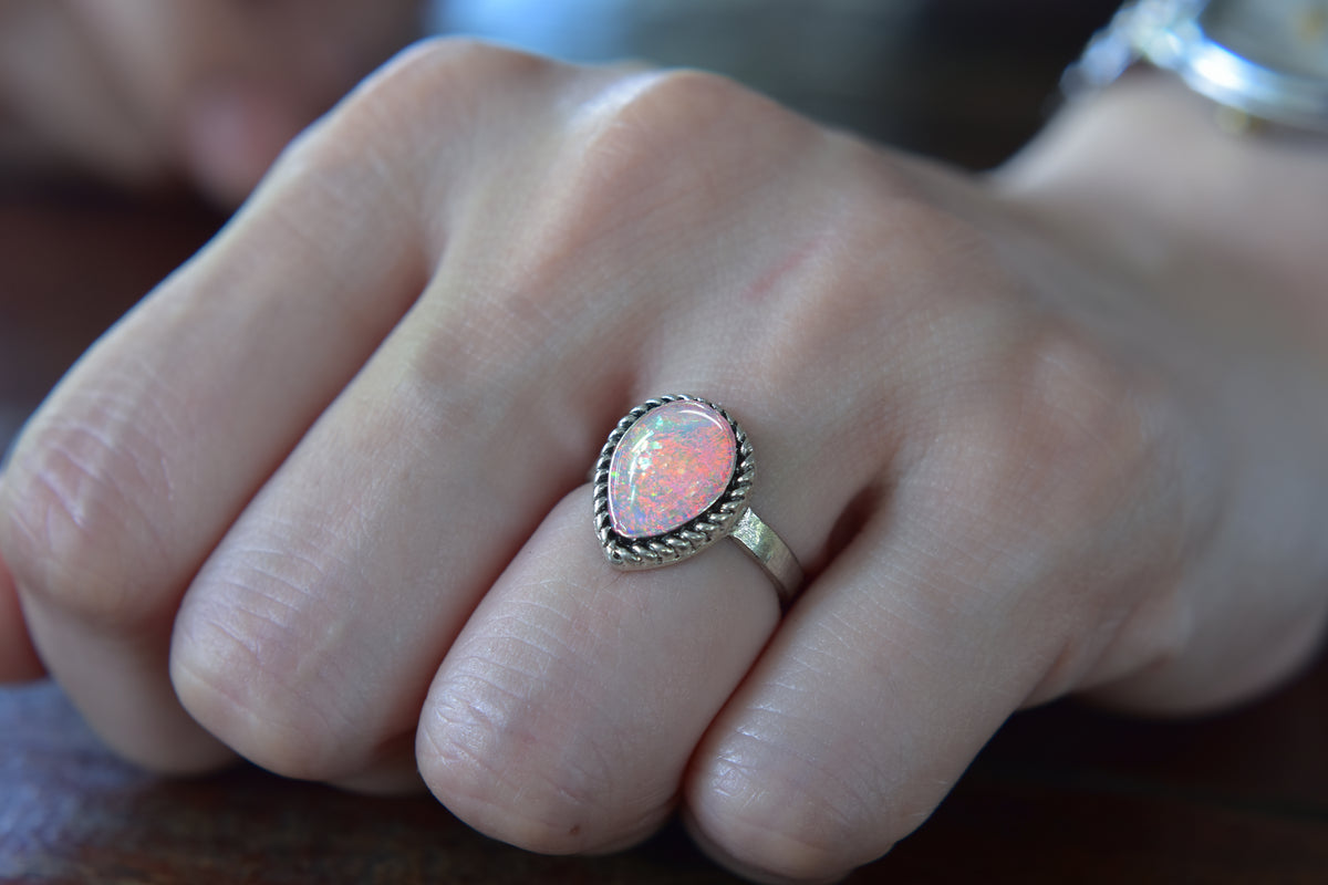 Handgefertigter Silberring mit einem funkelnden Opal-Edelstein in Tropfenform.