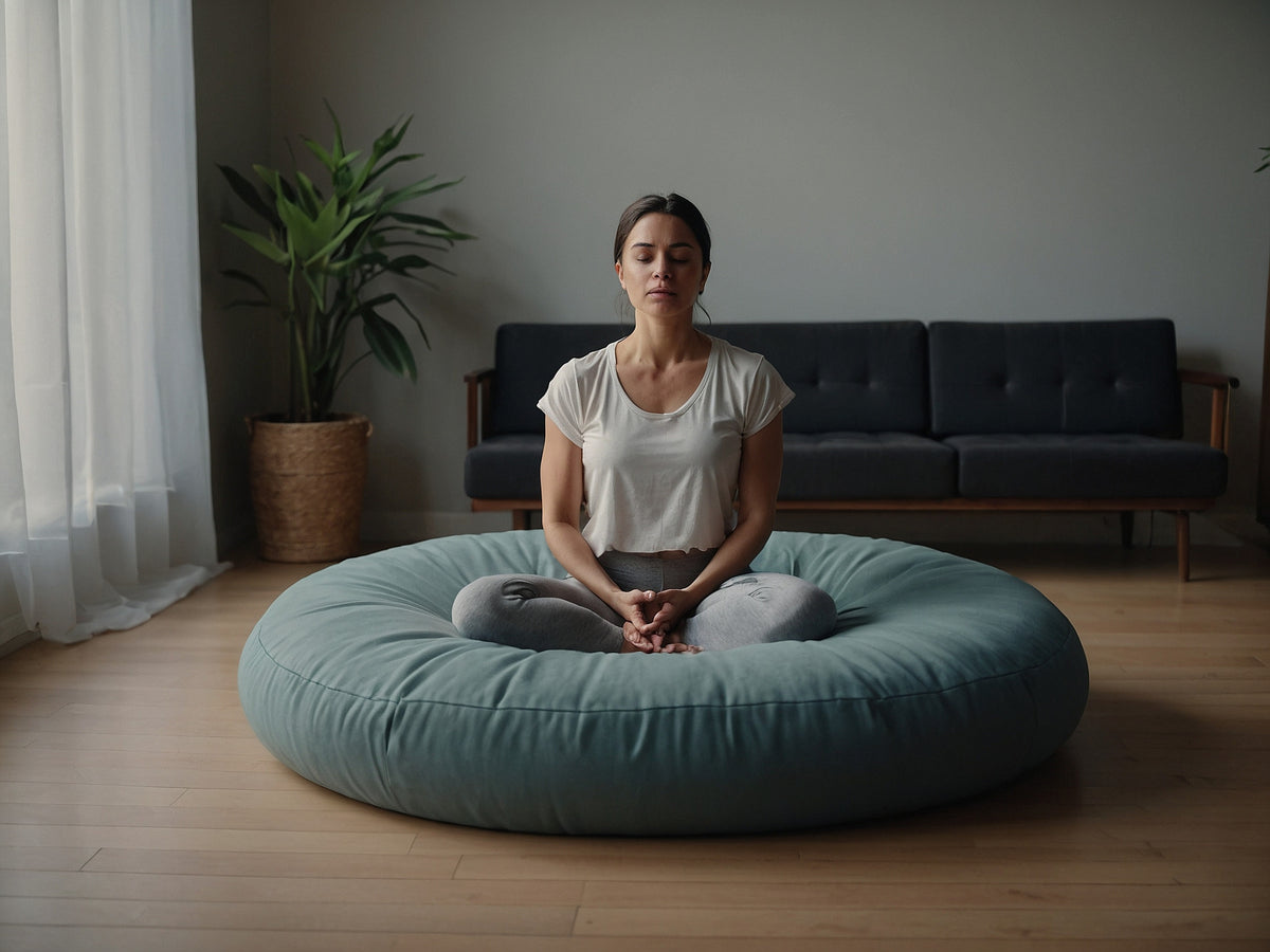Meditierende Frau in Yoga-Pose auf einem großen, runden Sitzkissen im Wohnzimmer.
