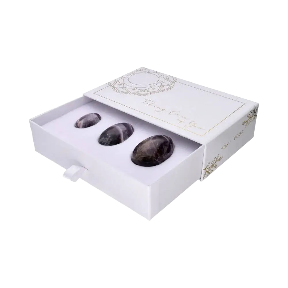 Drei polierte Amethyst-Yoni-Eier für therapeutisches Zubehör, von Vives de la Cortada SCP, auf weißem Hintergrund.