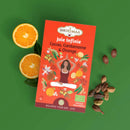 Ein roter bio-kräutertee joie infinie karton mit kakao-schalen, orange schale und einer meditierenden frau darauf