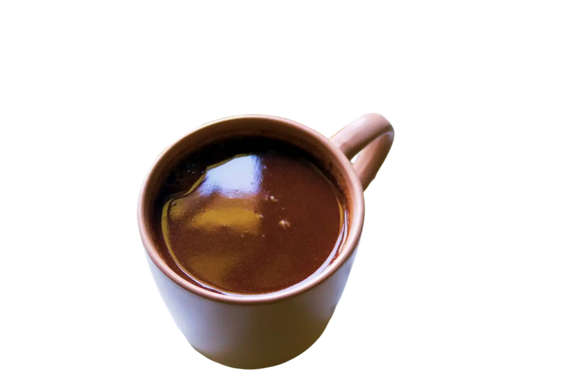 Ein warmer, reichhaltiger brauner roher kakao in einer matten terrakotta-tasse aus zeremonieller roher kakaostücken 50g