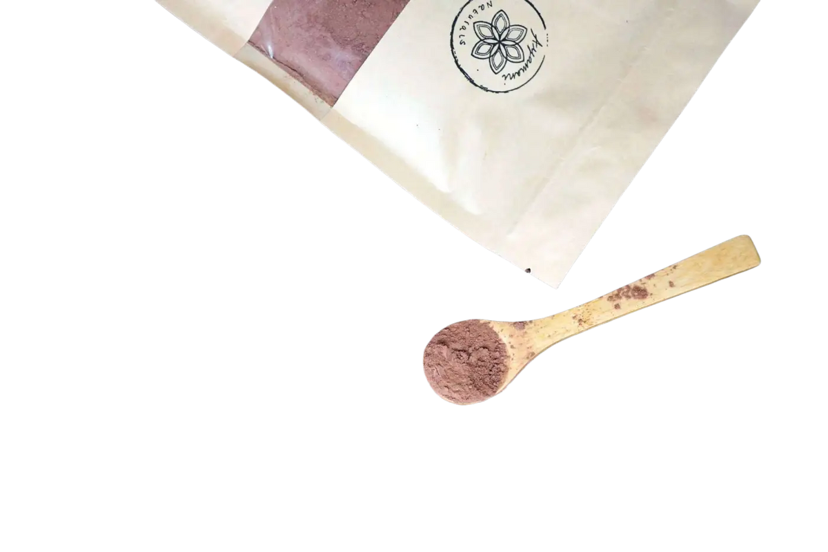 Ein holzlöffel mit reichhaltigem braunem zeremoniellen roher kakao neben einer papiertüte roher kakao auf holz