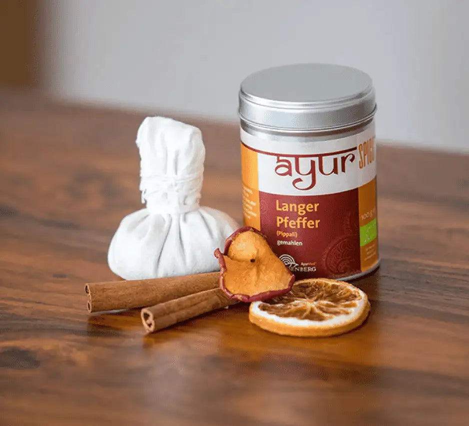 Ayur Bio-Langer Pfeffer gemahlen mit Zimtstangen und getrockneten Zitrusfrüchten auf Holztisch